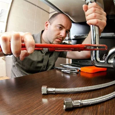 Handwerker arbeitet am Siphon.